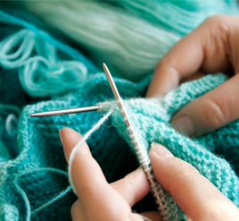 Person knitting with thin green yarn. 