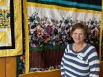 Image of staff in front of a hanging quilt