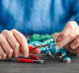 Person making blue and green beaded jewelry.