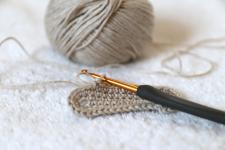 Image of a ball of yarn with the start of a small crocheting project and crochet hook.
